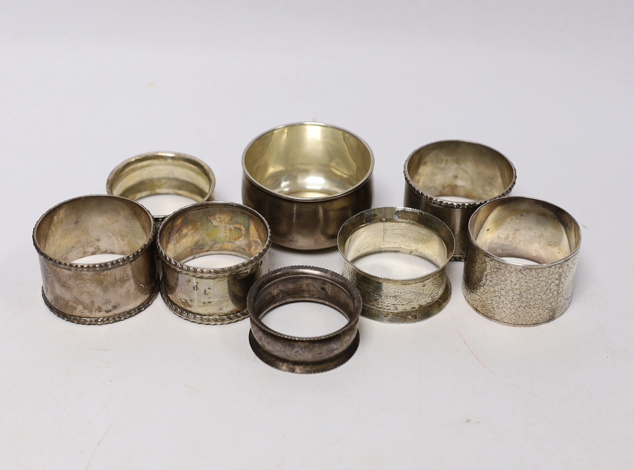 Seven assorted silver napkin rings and a small silver bowl